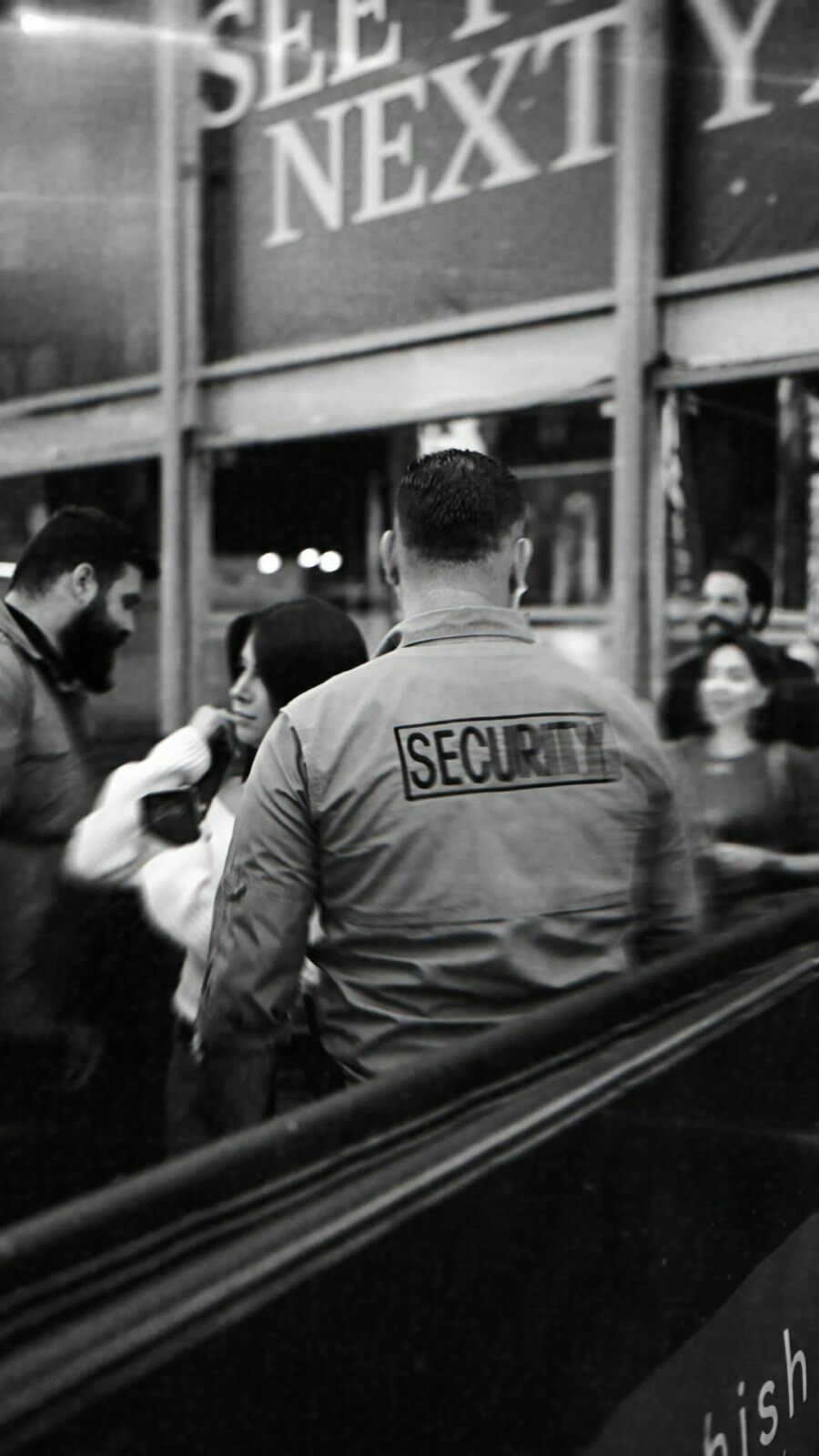 Agent in a security jacket managing guests at an entrance